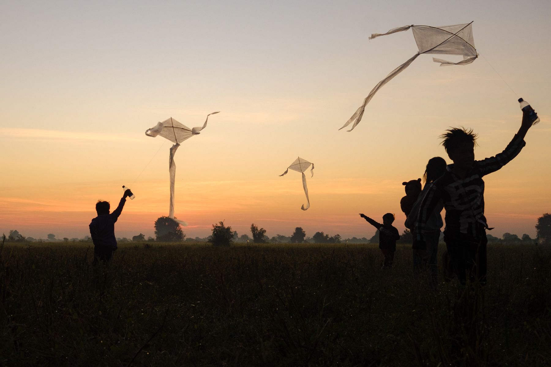 A Family flies kites together against a golden sunset sky